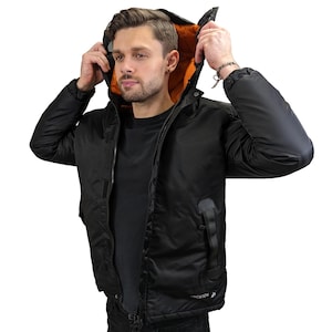 May include: Black hooded jacket with an orange lining and a zipper closure. The jacket has a logo on the bottom left side that says "Occasion".