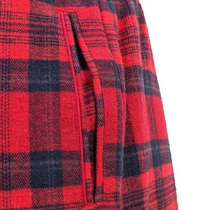 Puede incluir: Tela de franela a cuadros rojos y negros con un bolsillo cosido. La tela tiene un tejido de espiga.