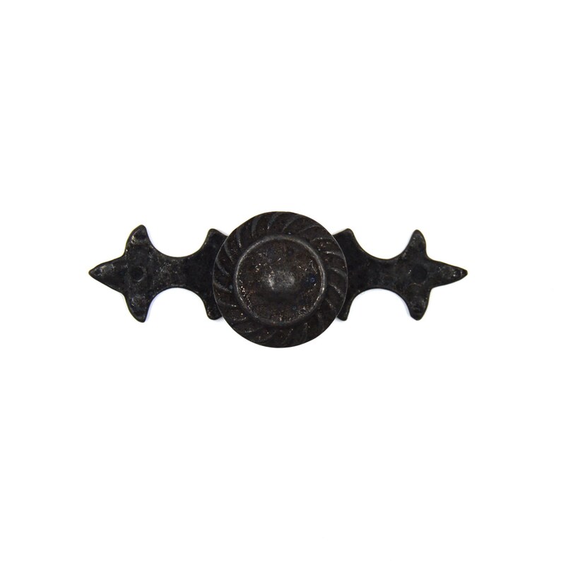 May include: Black metal drawer pull with a decorative, round knob and ornate, pointed ends.