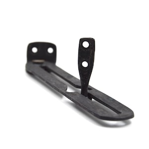 May include: A black metal bracket with a rectangular base and a vertical, slotted arm. The bracket has two holes on the base and two on the arm. The object is set against a white background.