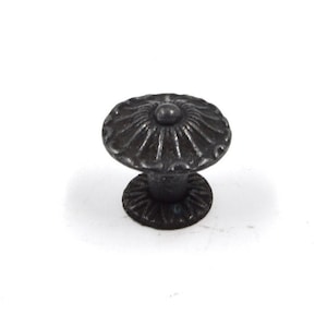 May include: Black metal cabinet knob with a decorative floral design. The knob has a round base and a raised center.