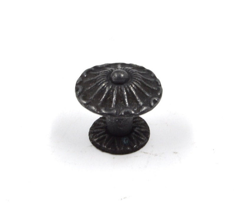 May include: Black metal cabinet knob with a decorative floral design. The knob has a round base and a raised center.