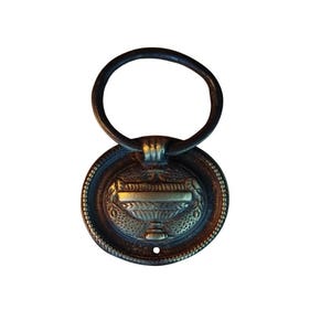 以下が含まれることがあります： 円形のハンドルと装飾的な丸いバックプレートを備えた、アンティークブロンズ調の引き出しプル。 バックプレートには、花瓶のエンボス加工のデザインと複雑なディテールが施されています。 バックプレートの下部に小さな穴が見えます。