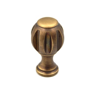 以下が含まれることがあります： フルーテッドデザインの丸いアンティークブラスキャビネットノブ。ノブはわずかに丸みを帯びたベースになっています。