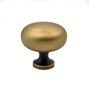 Puede incluir: Un pomo de armario redondo de latón cepillado con una parte superior ligeramente abovedada y una base cilíndrica corta.