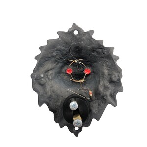May include: Black metal door knocker shaped like a lion's head with red LED lights and wiring visible in the back.