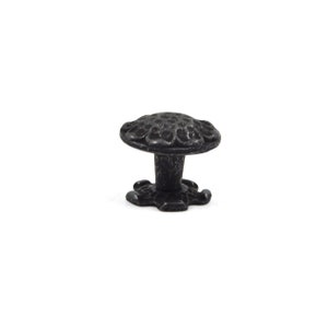 Puede incluir: Pomo de armario de hierro fundido negro con un dise&ntilde;o floral decorativo. El pomo tiene una parte superior redonda y una base en forma de estrella.