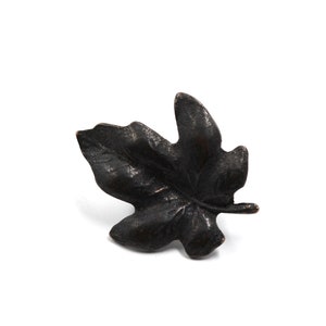 May include: A black metal leaf-shaped decorative accent. The leaf has a detailed, textured surface.