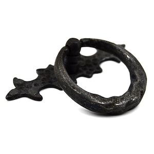 May include: Black metal ring pull handle with a decorative, ornate,  cross-shaped backplate.