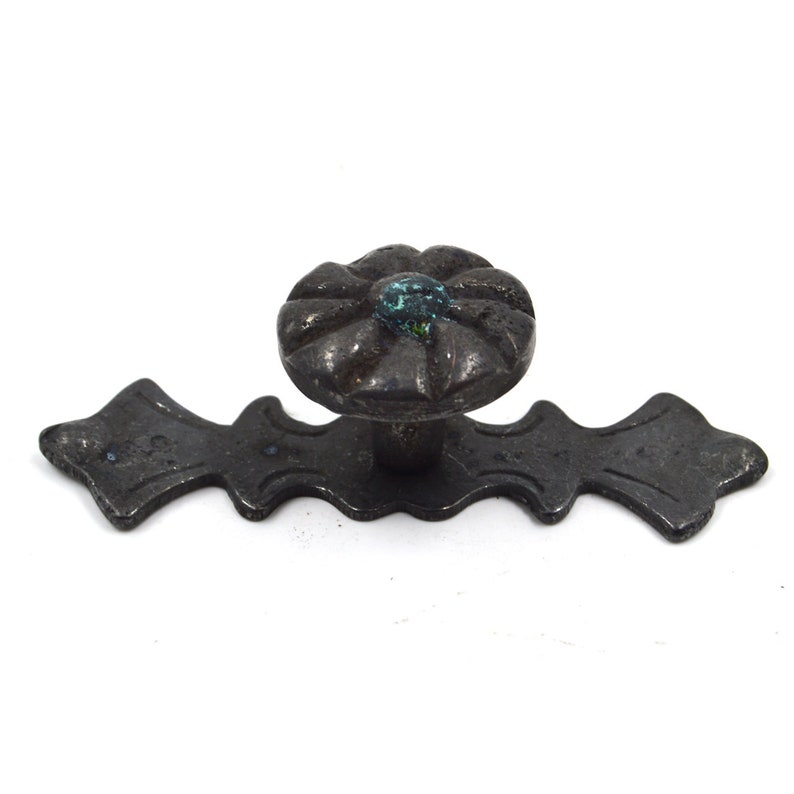 Pu&ograve; includere: Pomo per armadio in metallo nero con un design floreale decorativo e un centro turchese.