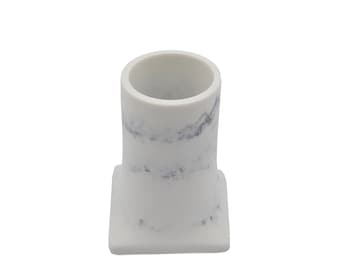May include: White ceramic pencil holder with a marble pattern. The holder has a square base and a cylindrical top.