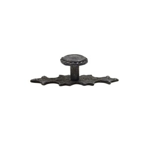 Może przedstawiać: Czarny metalowy gałka do szafki z ozdobnym, bogatym wzorem. Gałka ma okrągły wierzchołek i płaską podstawę.