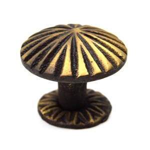 May include: A gold and brown cast iron mushroom-shaped cabinet knob with a fluted design.