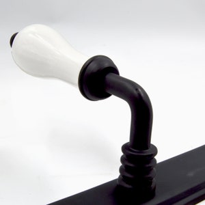May include: Black and white porcelain door handle with a white ceramic lever and a black metal base.