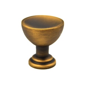 May include: A gold-toned cabinet knob with a rounded top and a fluted base.