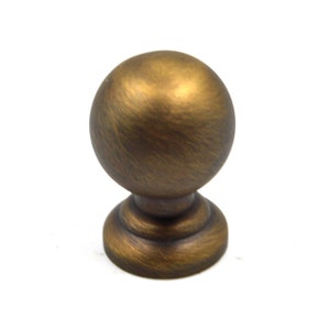 May include: A round, brushed brass cabinet knob with a slightly raised base.