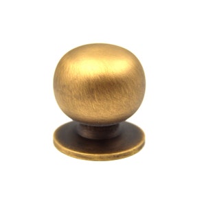May include: A round, brushed brass cabinet knob with a slightly raised base.