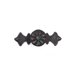 Pu&ograve; includere: Una maniglia per cassetto in metallo nero con un design floreale decorativo e un centro blu. La maniglia ha due estremit&agrave; decorative.