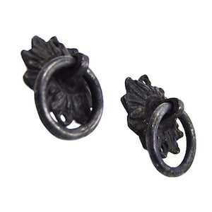 May include: Two antique-style drawer pulls with a dark, metallic finish. Each pull features a decorative leaf-shaped backplate and a circular ring handle. The hardware is designed for furniture restoration or adding vintage charm.