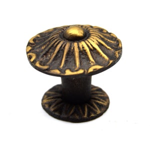 May include: A gold and black metal cabinet knob with a decorative floral design.