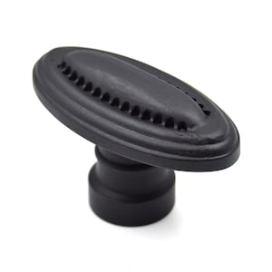 May include: Black oval cabinet knob with a decorative, patterned design. The knob has a round base.