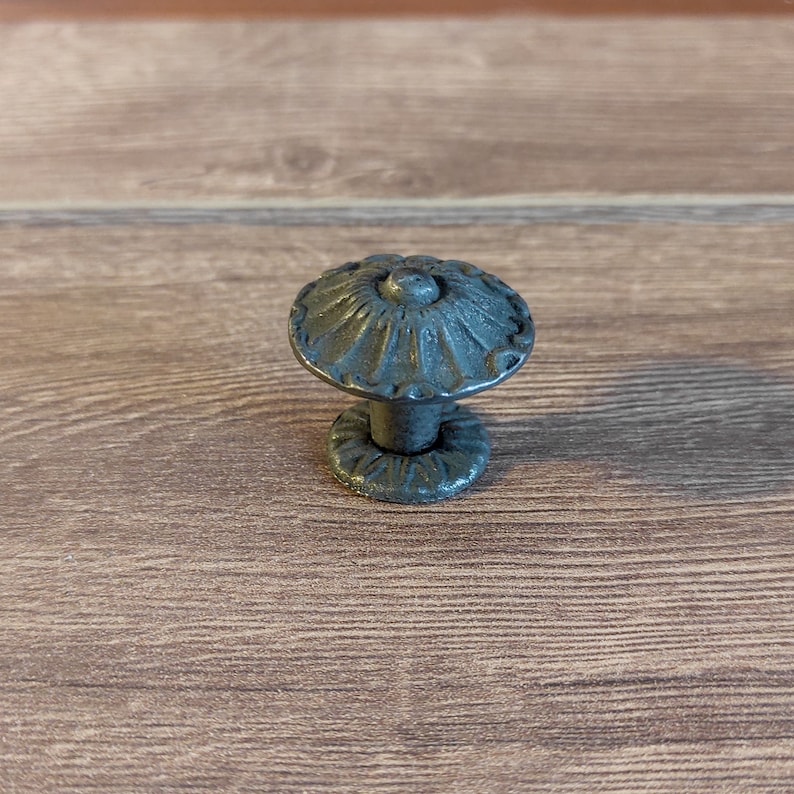 May include: A black metal cabinet knob with a decorative floral design.