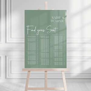 May include: A sage green wedding seating chart on a wooden easel. The chart features the names "Sadie & Dominic" and the text "Find your Seat" in elegant white script. Below, guest names are listed in columns.