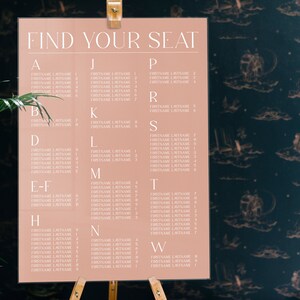 May include: A light pink seating chart with the text "FIND YOUR SEAT" at the top. The chart is divided into columns labeled with letters from A to W. Each column lists names with a first name and last name.