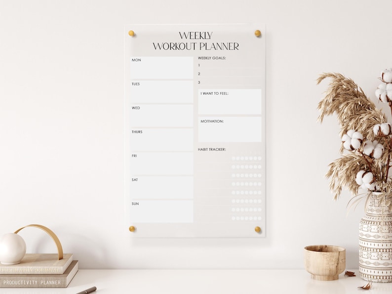 May include: A clear acrylic weekly workout planner with a beige background. The planner includes sections for weekly goals, how you want to feel, motivation, and a habit tracker.