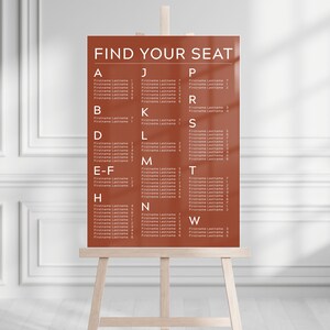 May include: A brown seating chart with white text that reads "FIND YOUR SEAT". The chart is divided into columns with letters from A to W and lists names under each letter.