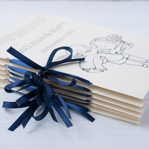 Pu&ograve; includere: Un fascio di programmi di nozze legati con un nastro di raso blu navy. I programmi color crema riportano i nomi "Melissa & Matt" e la data "4 settembre 2010", oltre a un disegno a tratto di una coppia.