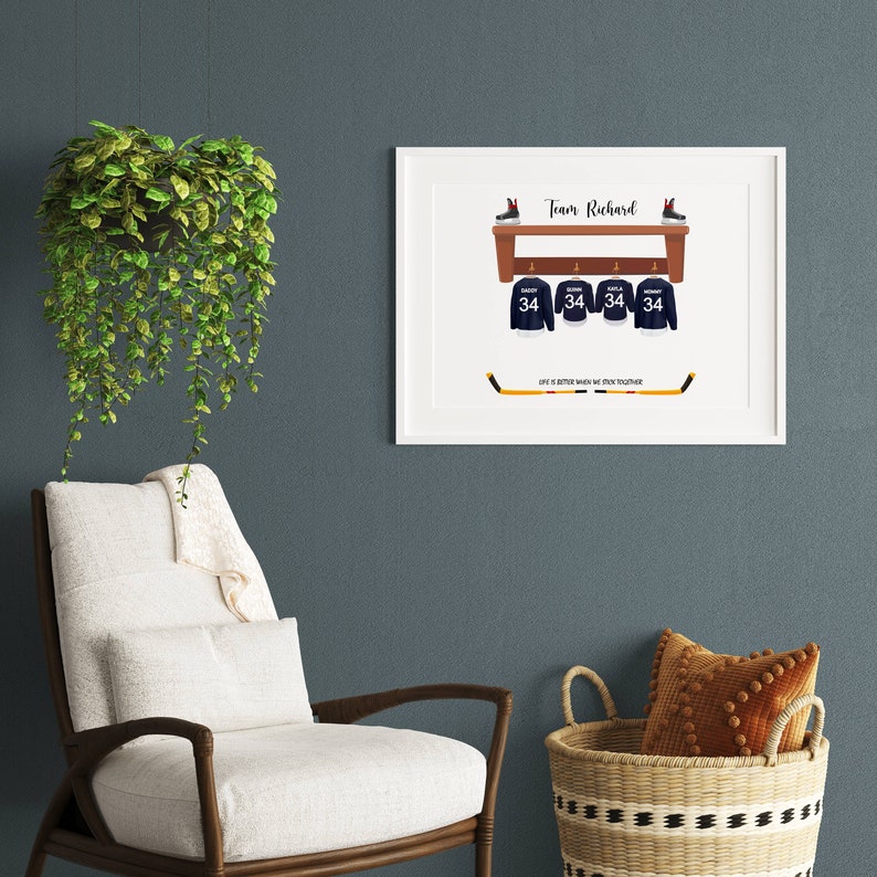 Op de afbeelding: Een wit ingelijst print met een hockeythema. De print toont een hockeystick, vier hockeytruien met nummer 34 en een plank met twee paar schaatsen. De tekst "Team Richard" en "Het leven is beter als we samenwerken" staat op de print.