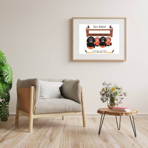 Op de afbeelding: Een ingelijst print met een hockeythema. Het toont een houten plank met drie hockeytruien die aan haken hangen. De truien zijn zwart met oranje accenten en hebben de nummers 34 en 26. De tekst "Team Richard" staat bovenaan de print. De tekst "Life is better when we cheer together" staat onderaan de print.
