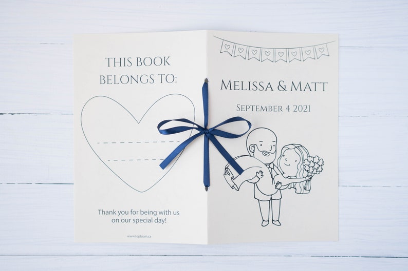 Pu&ograve; includere: Libro degli ospiti di nozze aperto con un nastro blu navy. La copertina recita "THIS BOOK BELONGS TO:" con un contorno a cuore. All'interno, presenta i nomi "MELISSA & MATT" e la data "SEPTEMBER 4 2021", insieme a un'illustrazione a cartoni animati.