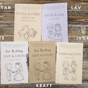 Pu&ograve; includere: Una collezione di programmi di nozze in vari colori, tra cui beige, bianco e avorio. Ogni programma presenta un'illustrazione di una coppia e include i nomi e la data del matrimonio. Sono disposti su una superficie di legno.