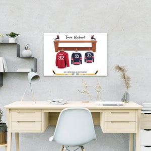 Op de afbeelding: Een witte print met een bruin houten plank met drie hockeytruien die aan haken hangen. De truien zijn rood, blauw en wit met het nummer 32 op elk. De tekst "Team Richard" staat bovenaan de print. De tekst "Life is better when we stick together" staat onderaan de print.