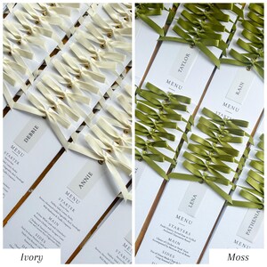 May include: Ivory and moss green wedding menu cards. The ivory cards have cream-colored bows with gold accents. The moss green cards have green bows. Each card has a guest's name and the word "MENU" printed on it.