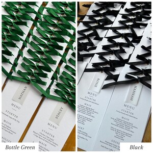 May include: Two sets of wedding menu cards, one with bottle green ribbons and the other with black ribbons. Each card has a menu with starter and main course options. The names Nathan, Stacey, Rosie, and Hannah are printed on the cards.