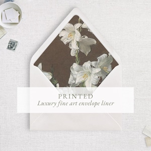 May include: White envelope with a printed luxury fine art envelope liner featuring a botanical illustration of white lilies on a brown background. The text "PRINTED Luxury fine art envelope liner" is displayed on the front.