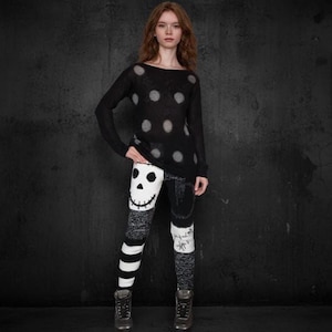 Può includere: Top nero a maniche lunghe con grandi pois grigi. I leggings sono neri e bianchi con un disegno a teschio sul davanti e un motivo a righe sulla gamba sinistra. L'outfit è completato da stivali grigio scuro.
