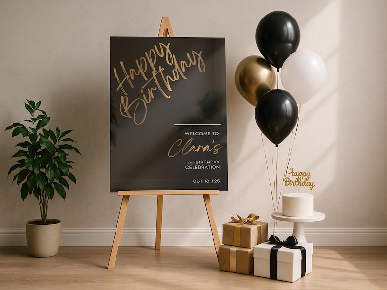 以下が含まれることがあります： 「Happy Birthday」と「Welcome to Clara's」のゴールドの文字が入った黒い看板がある誕生日のシーン。風船、プレゼント、そして「Happy Birthday」のケーキトッパーが付いたケーキが、お祝いの装飾を完成させています。