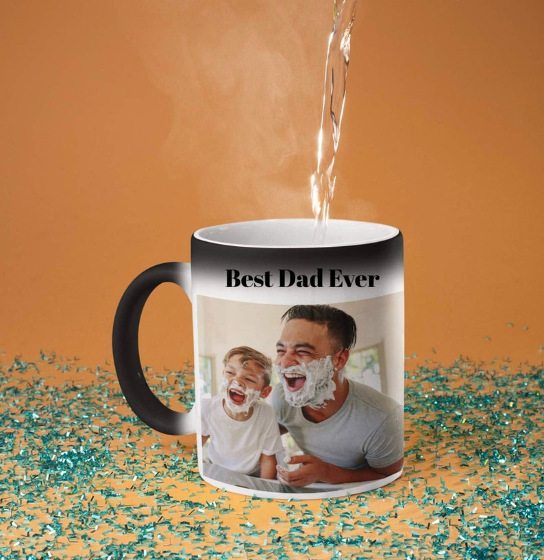 May include: Black and white color changing mug with a photo of a father and son laughing. The mug reads "Best Dad Ever" in black text.