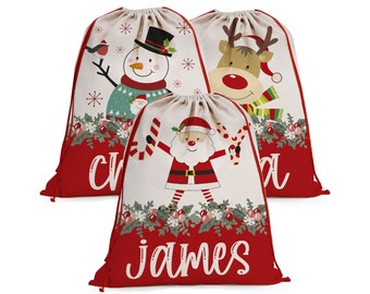 May include: Three red and white Christmas gift bags with drawstring closures. The bags feature different holiday characters: a snowman, a reindeer, and Santa Claus. The bags are personalized with the names "Chris", "Mia", and "James".