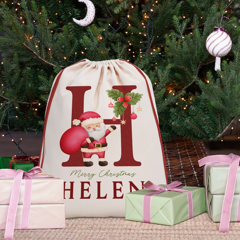 May include: A cream-colored Christmas gift bag with a red letter "H" and a cartoon Santa Claus holding a red bag. The bag has the text "Merry Christmas HELEN" printed on it.