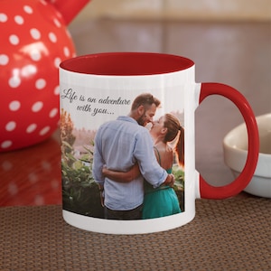 May include: White ceramic mug with a red rim and handle. The mug features a photo of a couple embracing and the text "Life is an adventure with you..." printed on the front.