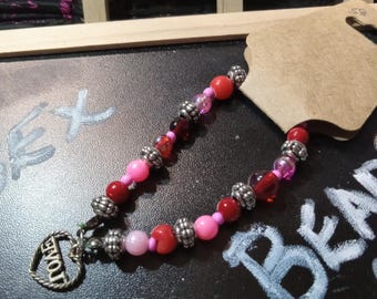 A pretty pink and red beaded bracelet with love charm.
