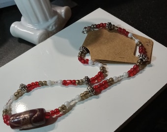 A red and white beaded necklace, with a red and gold center bead.