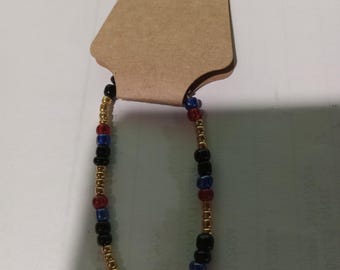 A pretty red, black,  blue and golden beaded bracelet.