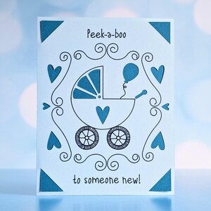 A cricut joy insert card with cutouts of a balloon, baby buggy, and hearts.  There are also ink drawings to complete the image.  The wording reads, "Peek-a-boo to someone new!"