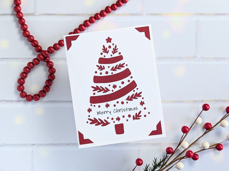 A greeting card featuring a Christmas tree that's made from cut out sprigs, circles, stars, and ribbon.